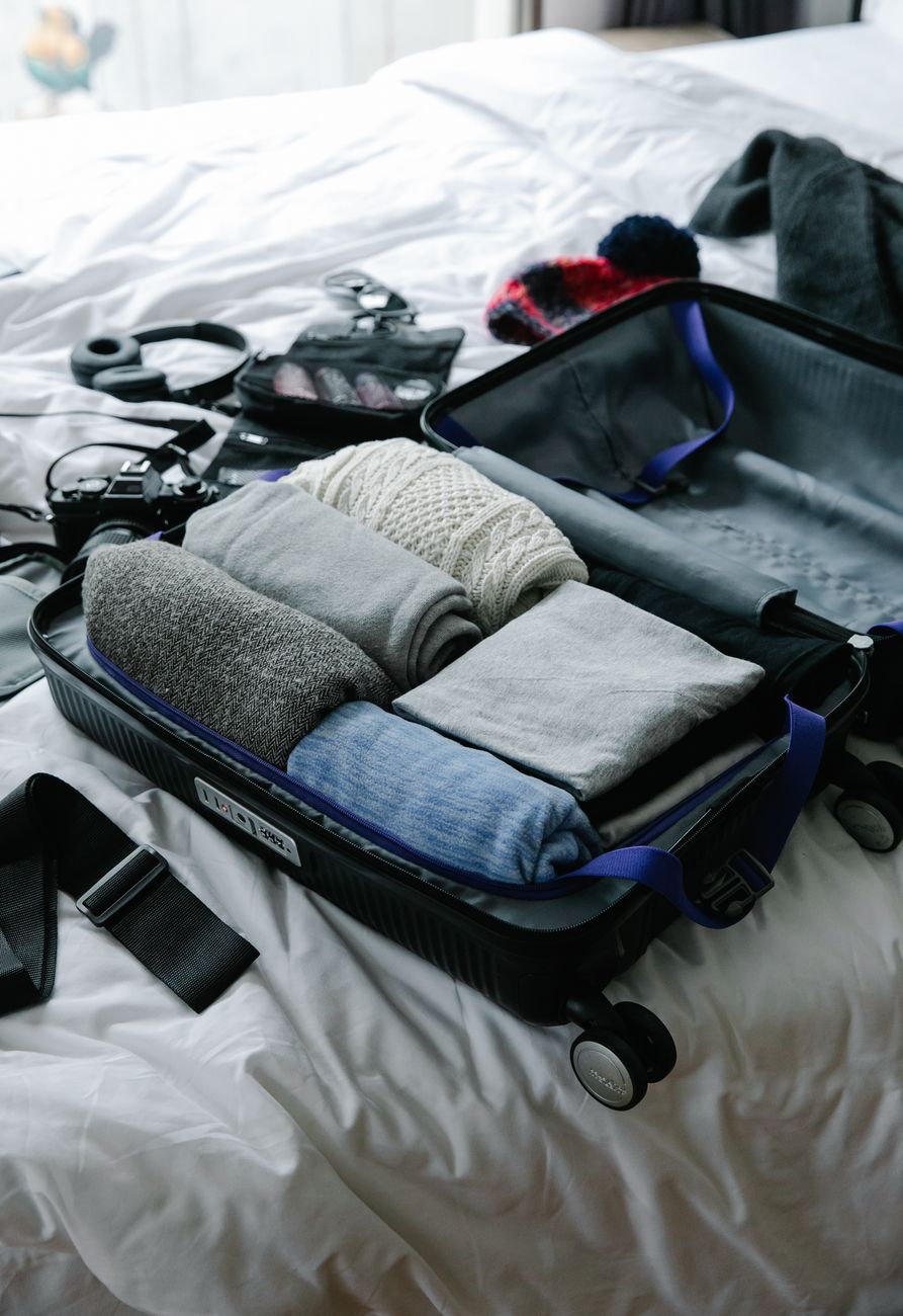 An open carry-on suitcase with folded clothes laid out beside it